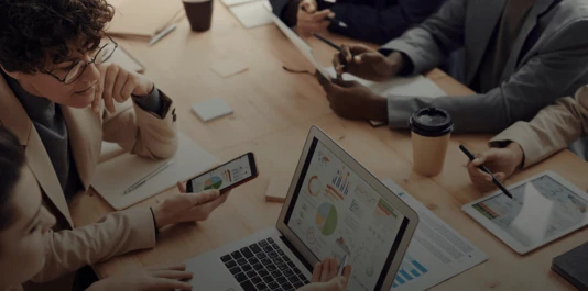 Menschen sitzen an einem Tisch und schauen sich Gesundheitsberichte an